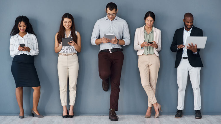 Verschiedene Personen, die nebeneinander an der Wand lehnen und verschiedene mobile Engeräte in Händen halten; Copyright Panthermedia