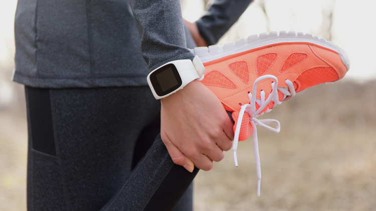 Frau beim Dehnen zur Vorbereitung auf Sporttraining mit einer Smartwatch am Armband, Copyright Fotolia