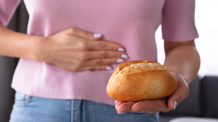 Frau hält ein Brötchen auf der Hand und fasst sich an den Bauch, Copyright Panthermedia