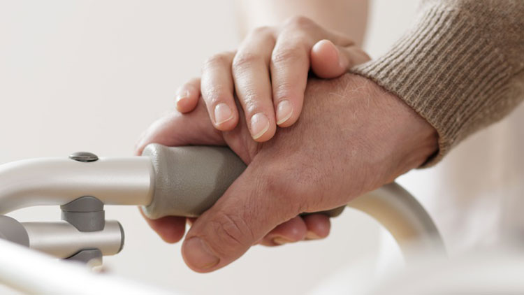 Hand eines Menschen auf dem Griff eines Rollators, die von einer anderen Hand gestreichelt wird; Copyright Fotolia